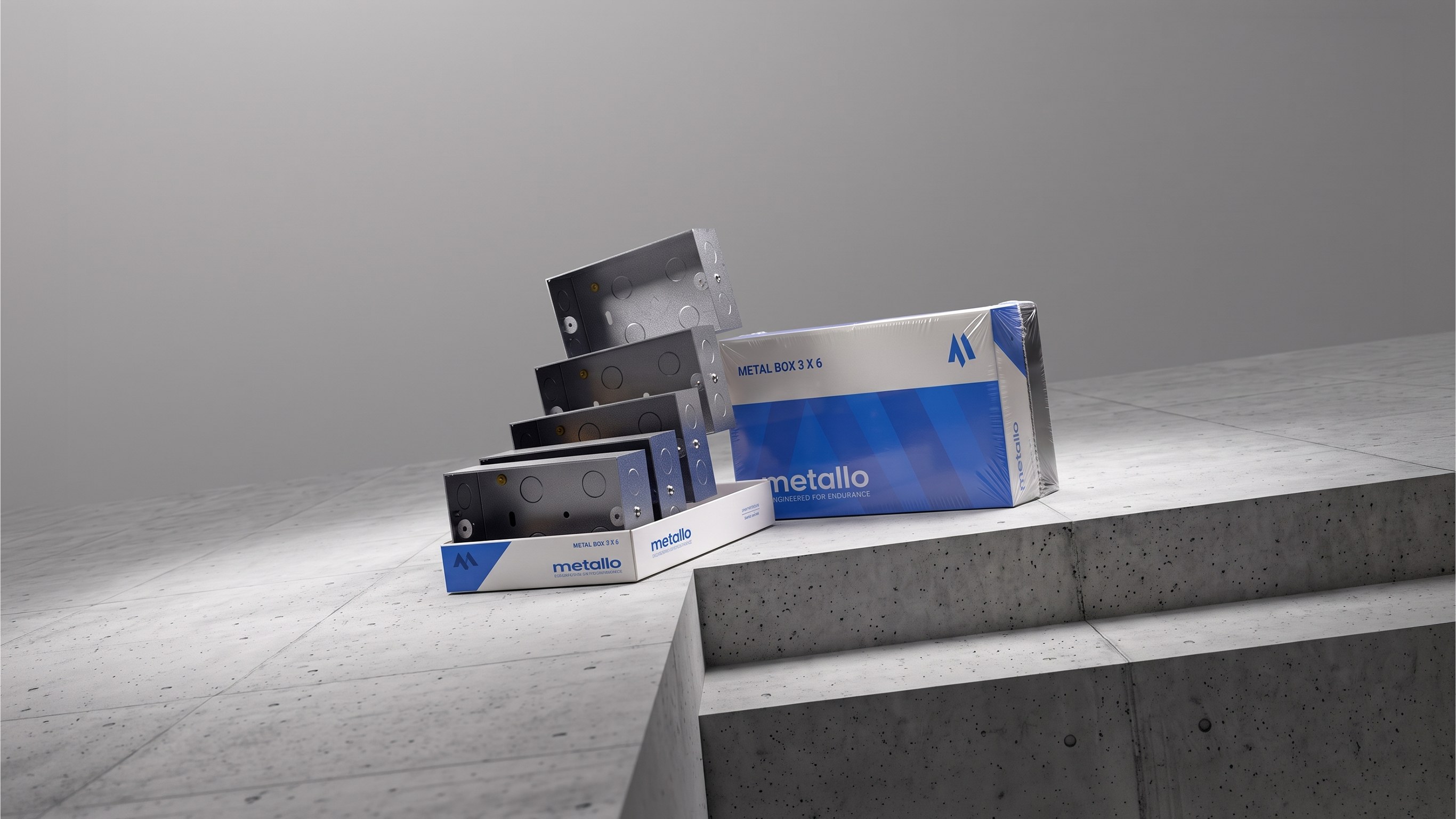 Metallo metal back boxes stacked on their tray beside a boxed Metallo Metal Box pack
