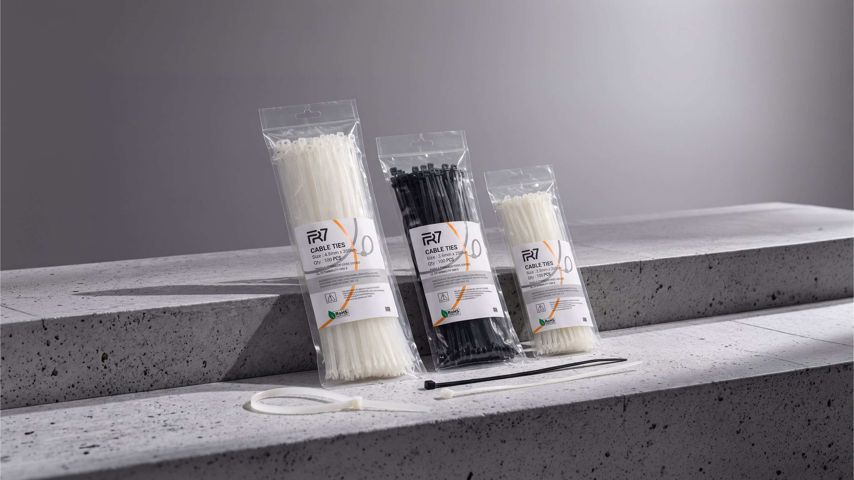 Three FR7 cable tie packs in natural and black, with loose ties on concrete steps